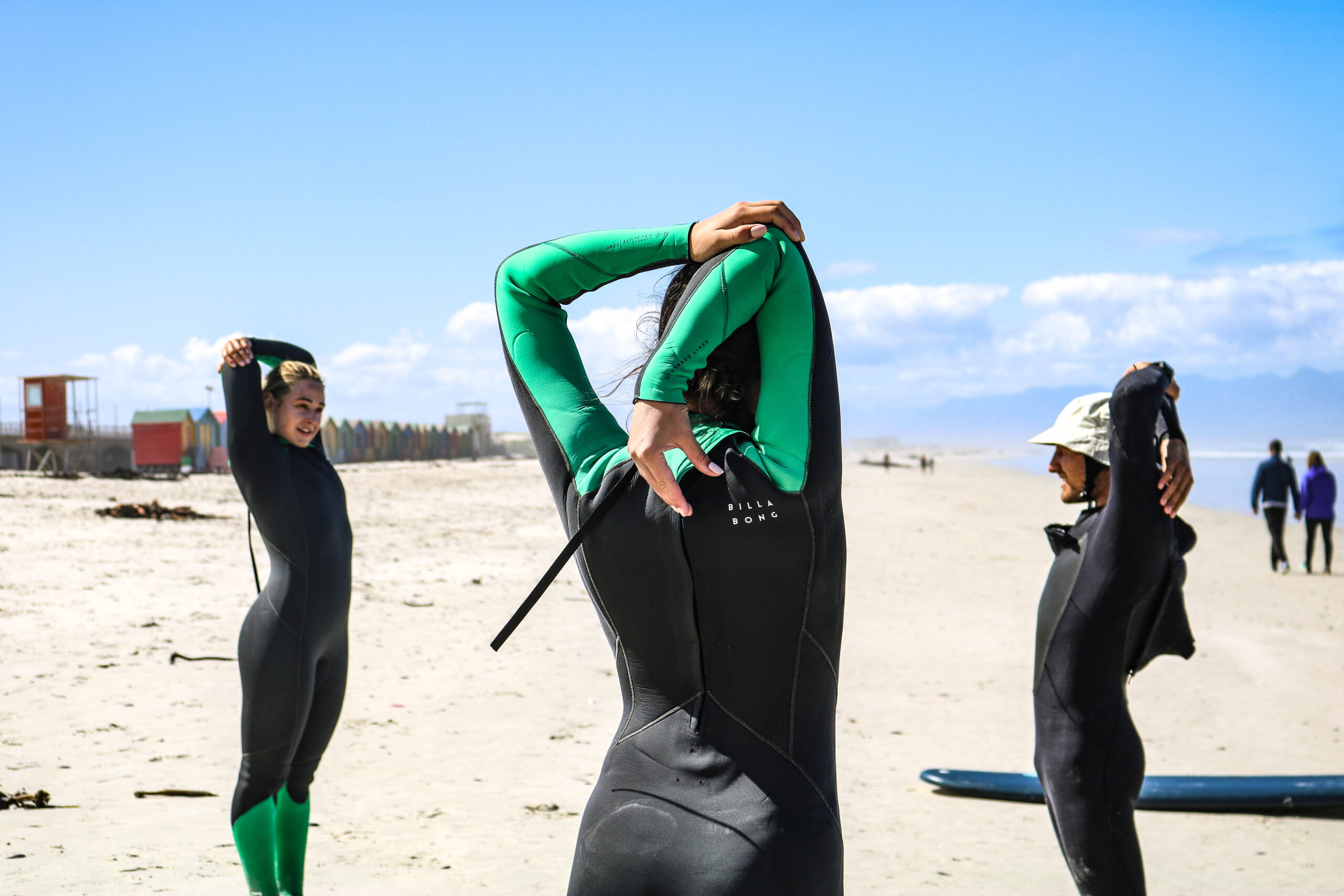 Surformer instructor stretching with two students with the beach and ocean in the background